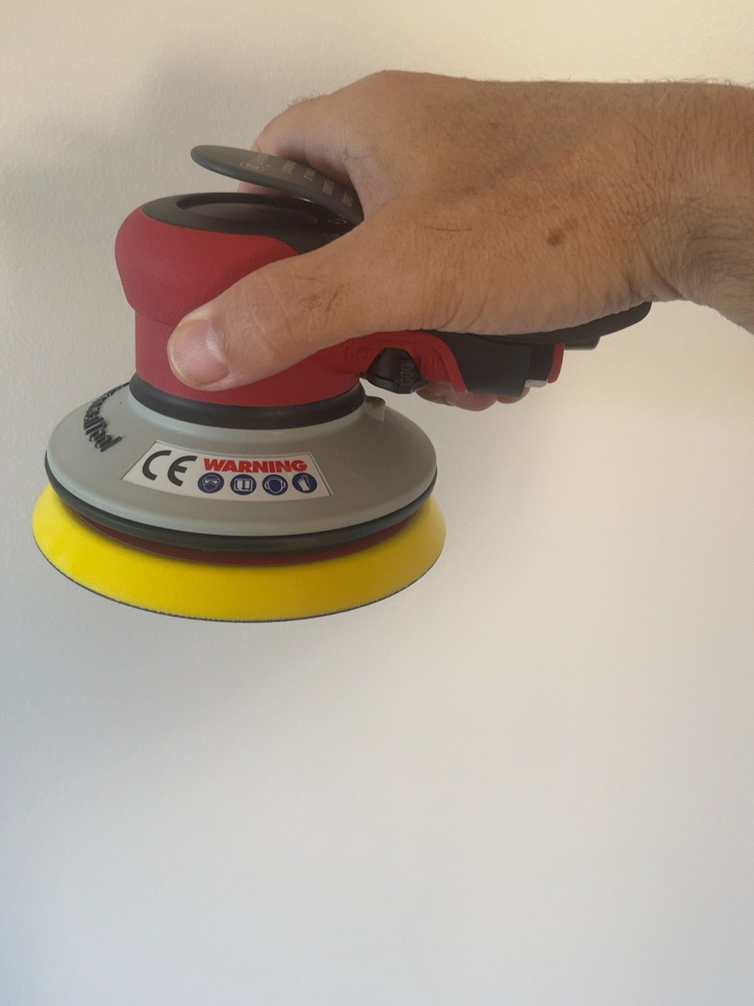 Actual Universal Tool 5-inch orbital sander held in hand, showing true size