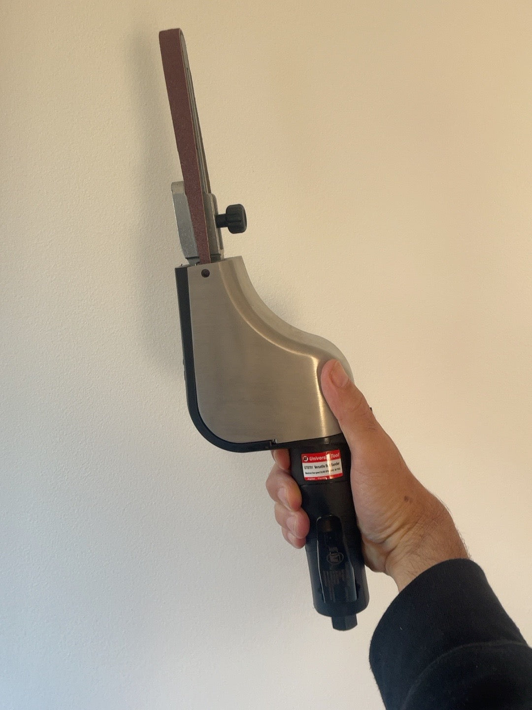 Actual UT8701 pneumatic belt sander held in hand, showing tool proportions and sanding arm